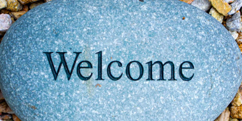 the word welcome carved into a river rock surrounded by colorful pebbles